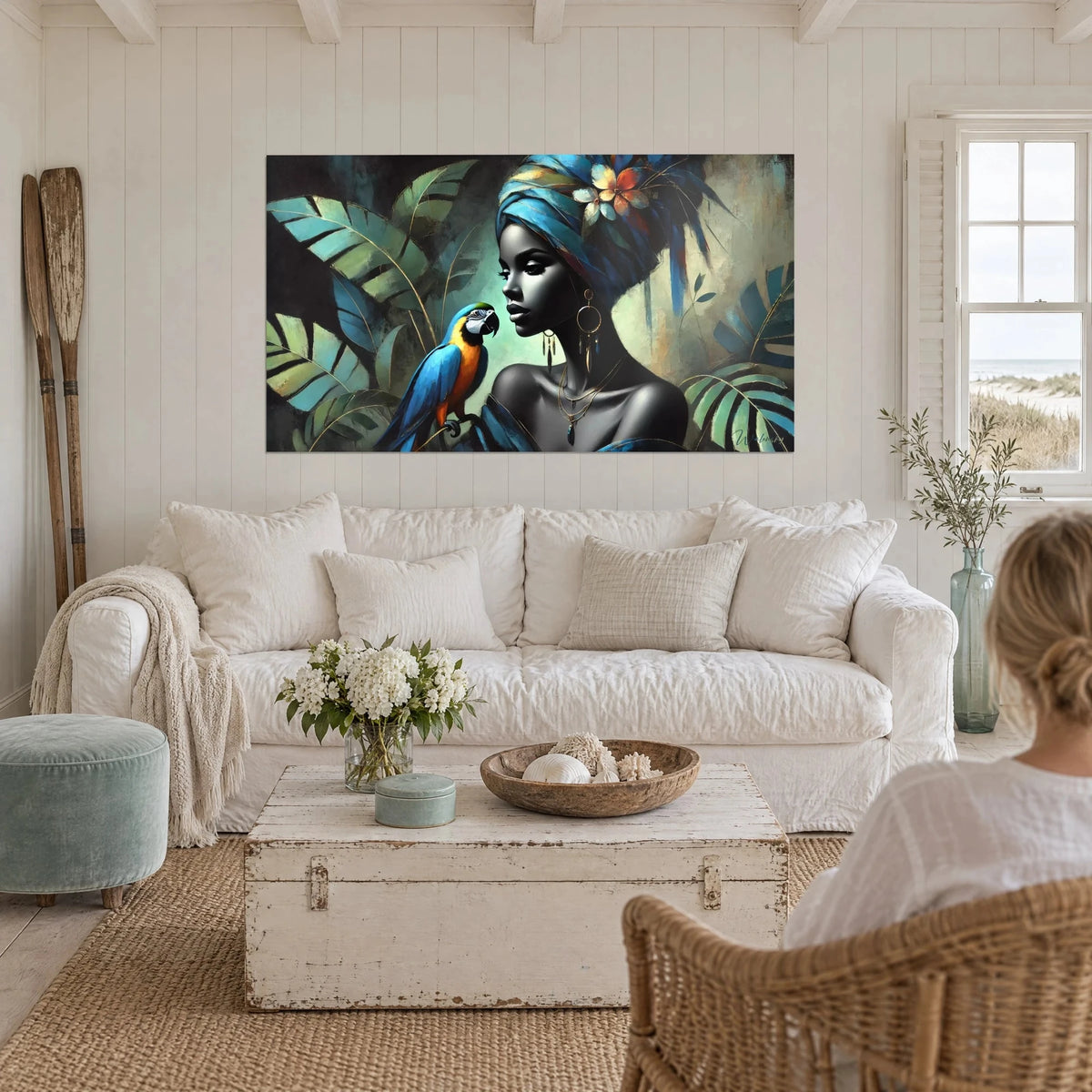 Schilderij van een tropische koningin met blauwe tulband en ara-papegaai, saliegroene bladerachtergrond, boven een bank in een lichte woonkamer