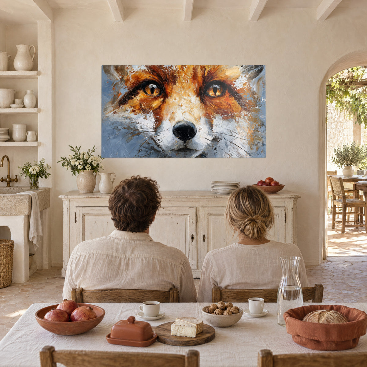 Quadro muso di volpe dipinto a spatola, arancio bruciato, bianco madreperla e grigio-azzurro, di fronte a una coppia seduta di spalle al tavolo della cucina del casolare