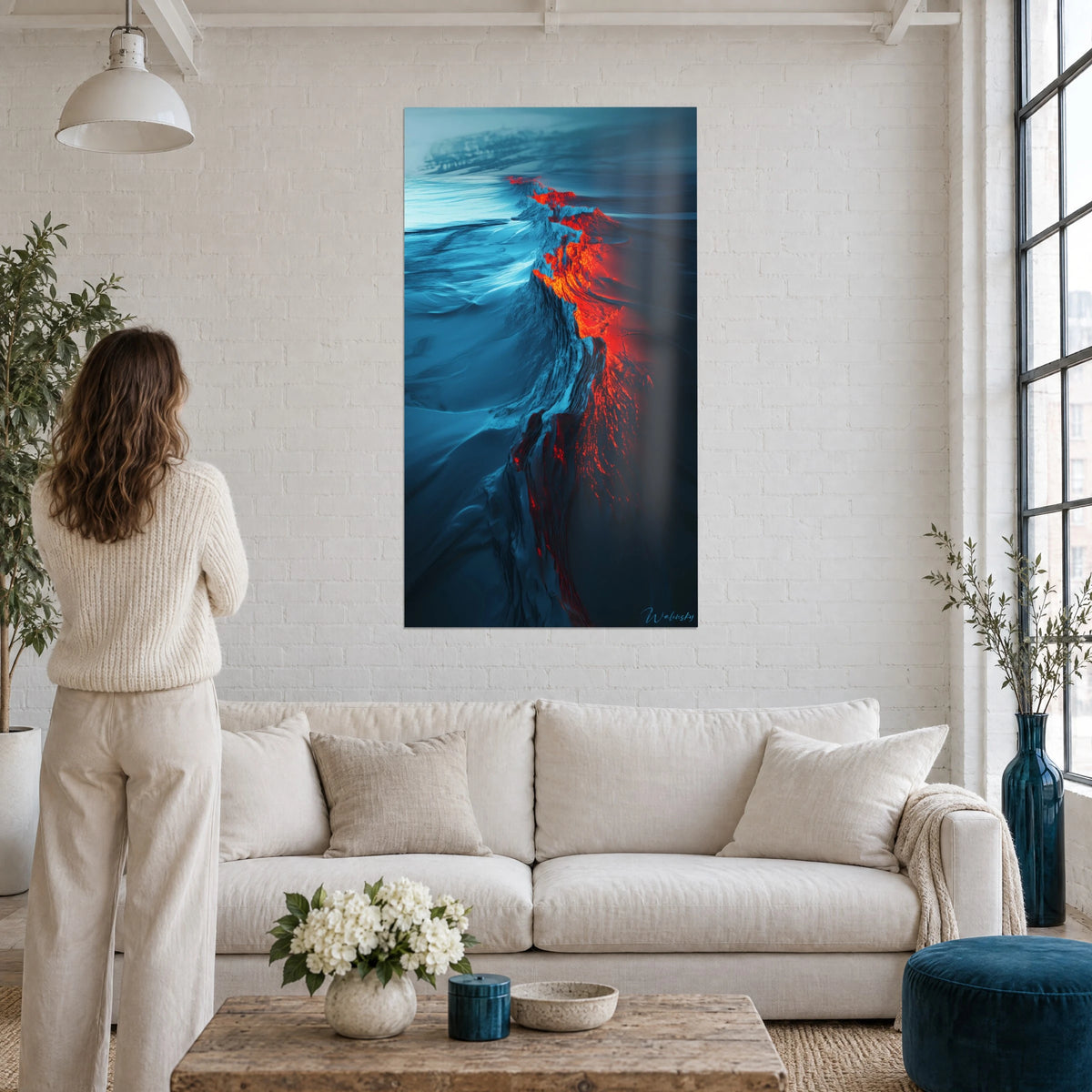 Cuadro de una falla de lava roja sobre hielo azul medianoche, mujer de espaldas, encima de un sofá en un salón luminoso
