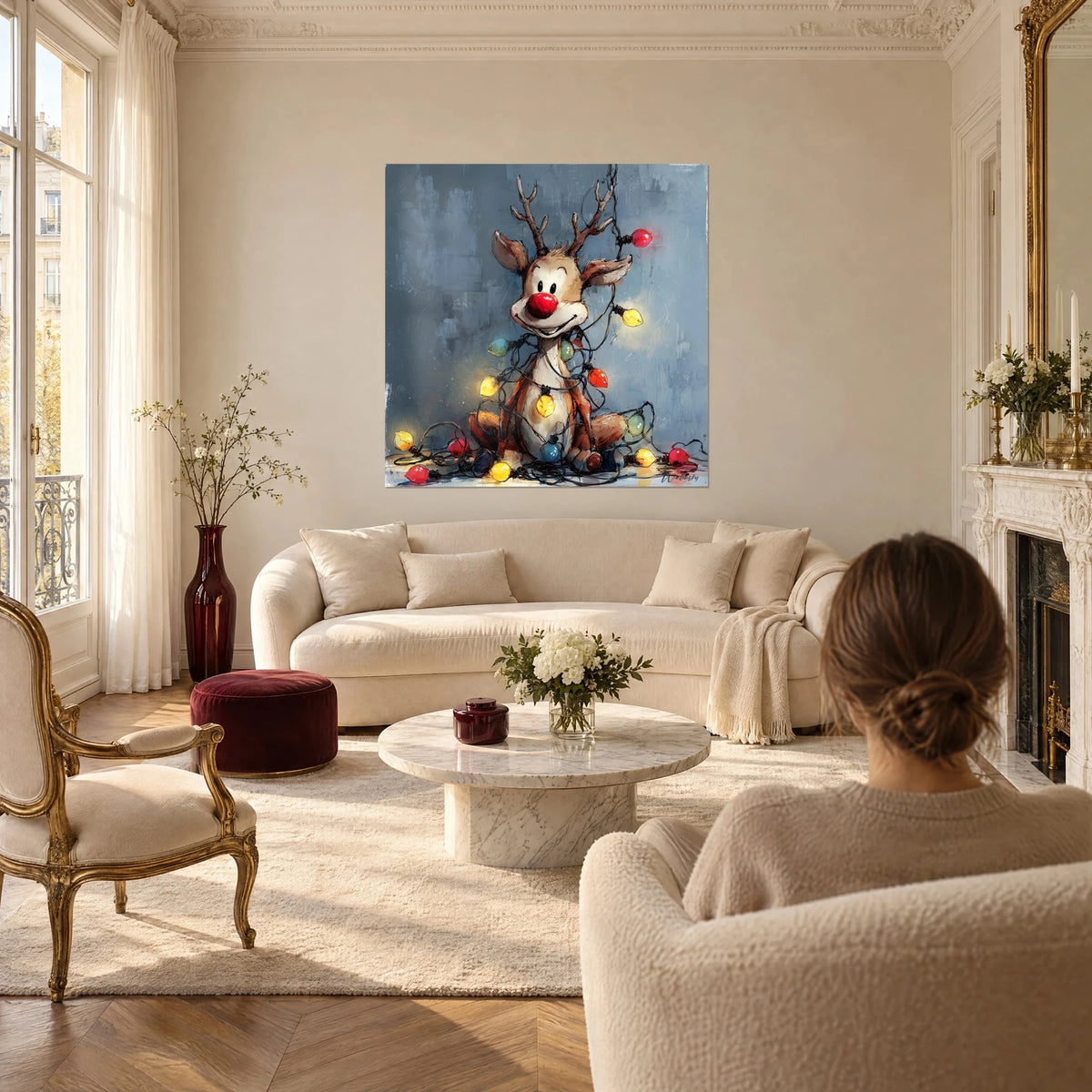 Tableau renne rieur au nez rouge, enroulé de guirlandes jaunes et rouges sur fond bleu ardoise, au-dessus d'un canapé dans un salon lumineux
