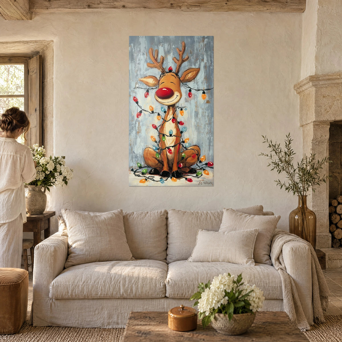 Wall art laughing reindeer with red nose, string of red and green bulbs, blue-grey background, above a sofa in a bright living room