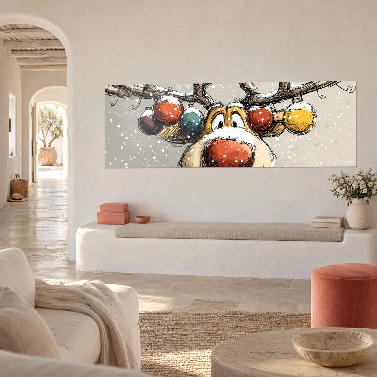 Quadro testa di cervo natalizio dagli occhi grandi e tondi, corna decorate con palline rosse, verdi e gialle, parete bianca di una casa mediterranea