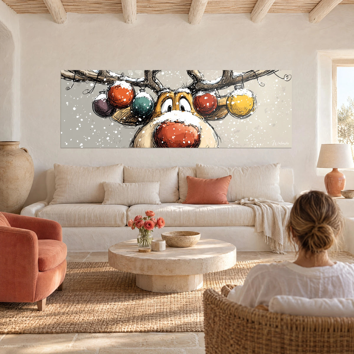 Quadro renna simpatica dal naso rosso coperto di neve, palline arancioni e gialle sulle corna, sopra un divano in un soggiorno luminoso