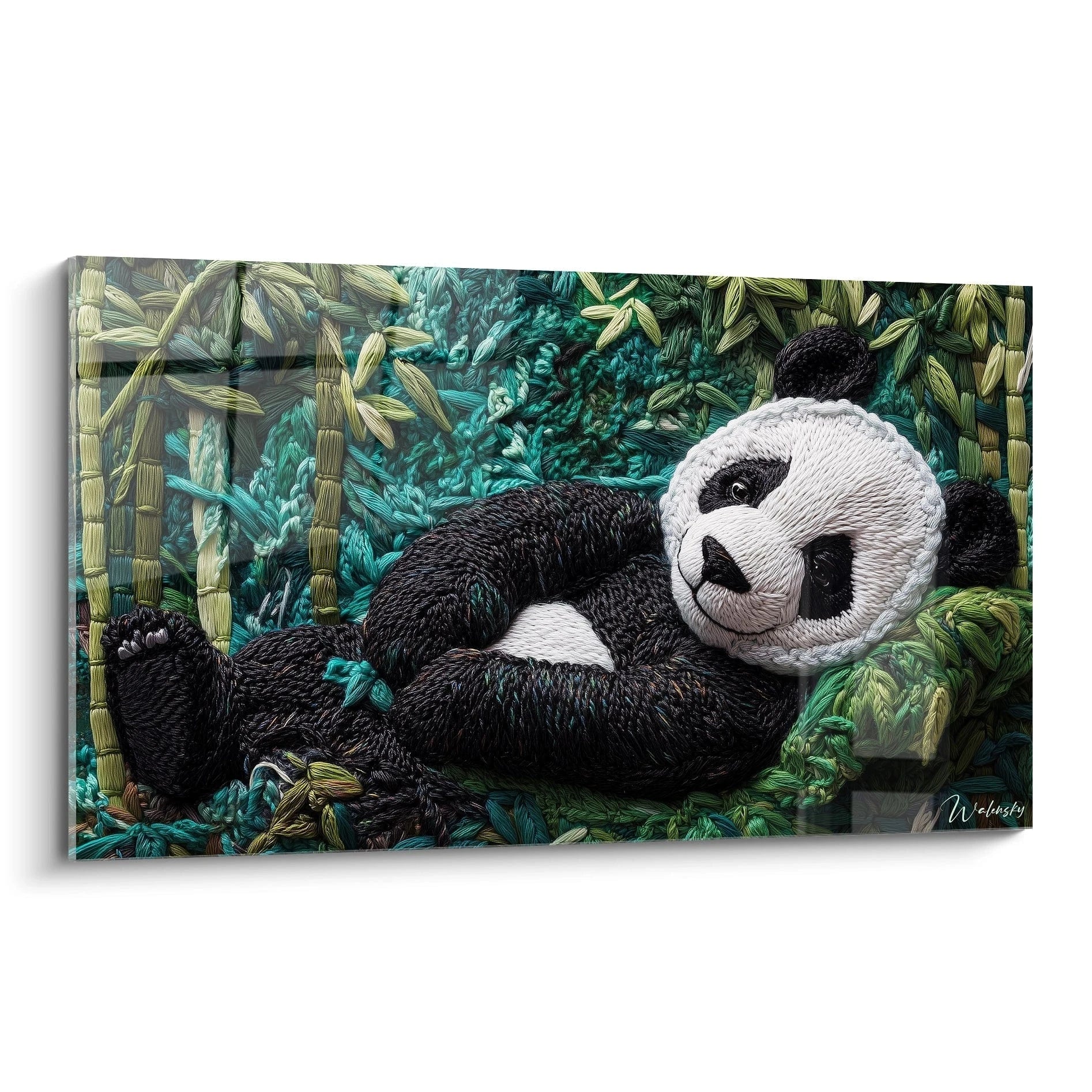 Un tableau panda en broderie textile représentant un panda allongé parmi des tiges de bambou, avec un pelage noir et blanc contrastant sur un fond turquoise et vert, créant une impression de relief et de texture tridimensionnelle grâce à la technique du crochet.
