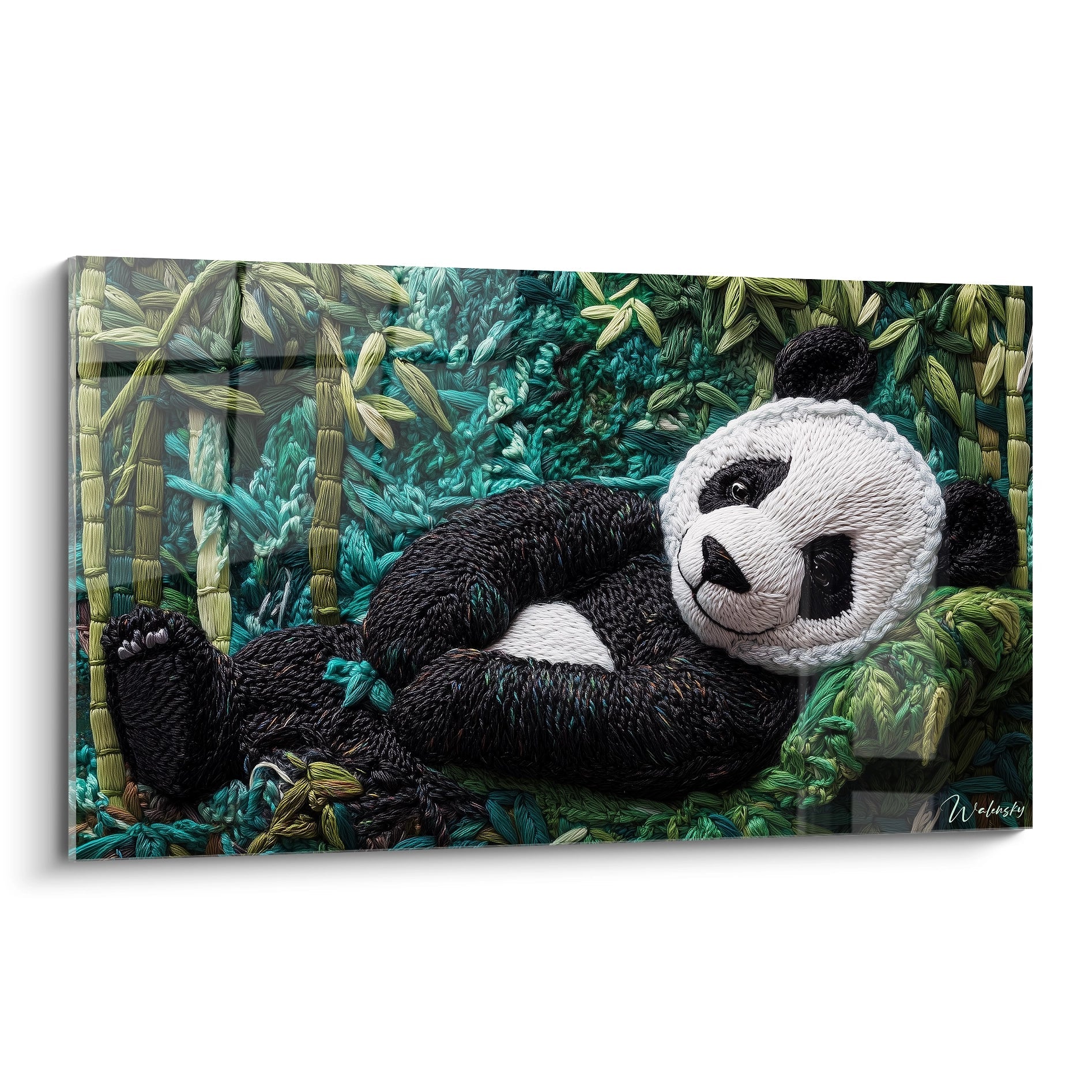 Un tableau panda en broderie textile représentant un panda allongé parmi des tiges de bambou, avec un pelage noir et blanc contrastant sur un fond turquoise et vert, créant une impression de relief et de texture tridimensionnelle grâce à la technique du crochet.
