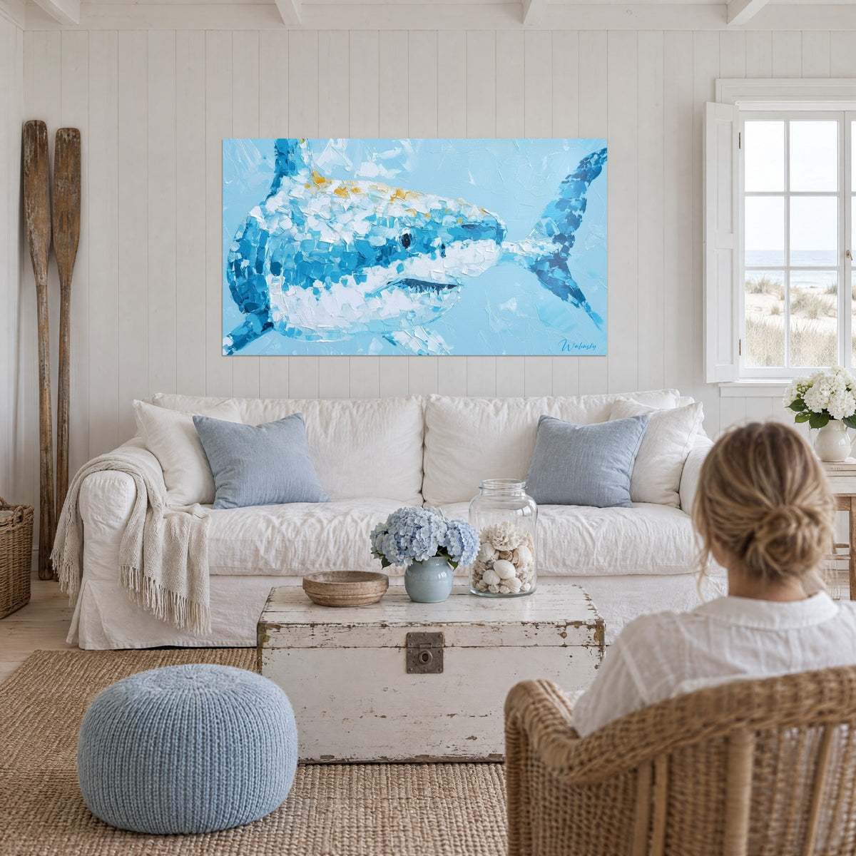 Tableau requin bleu et blanc aux touches dorées, peint au couteau, au-dessus d'un canapé dans un salon lumineux
