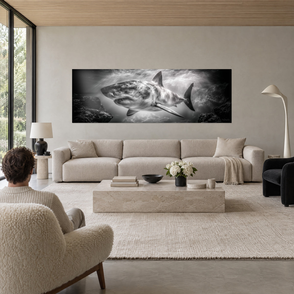 Schilderij van een grote witte haai die tussen de rotsen door glijdt, zwart-wit, lichtstralen die door het water filteren, boven een bank in een lichte woonkamer