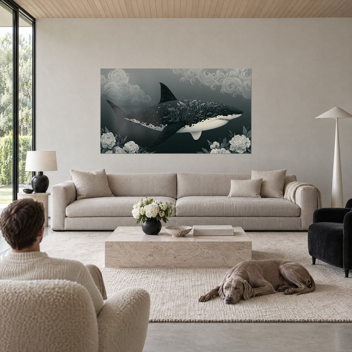 Cuadro tiburón negro con cuerpo decorado con volutas, peonías blancas y fondo gris pizarra, sobre un sofá en un salón luminoso