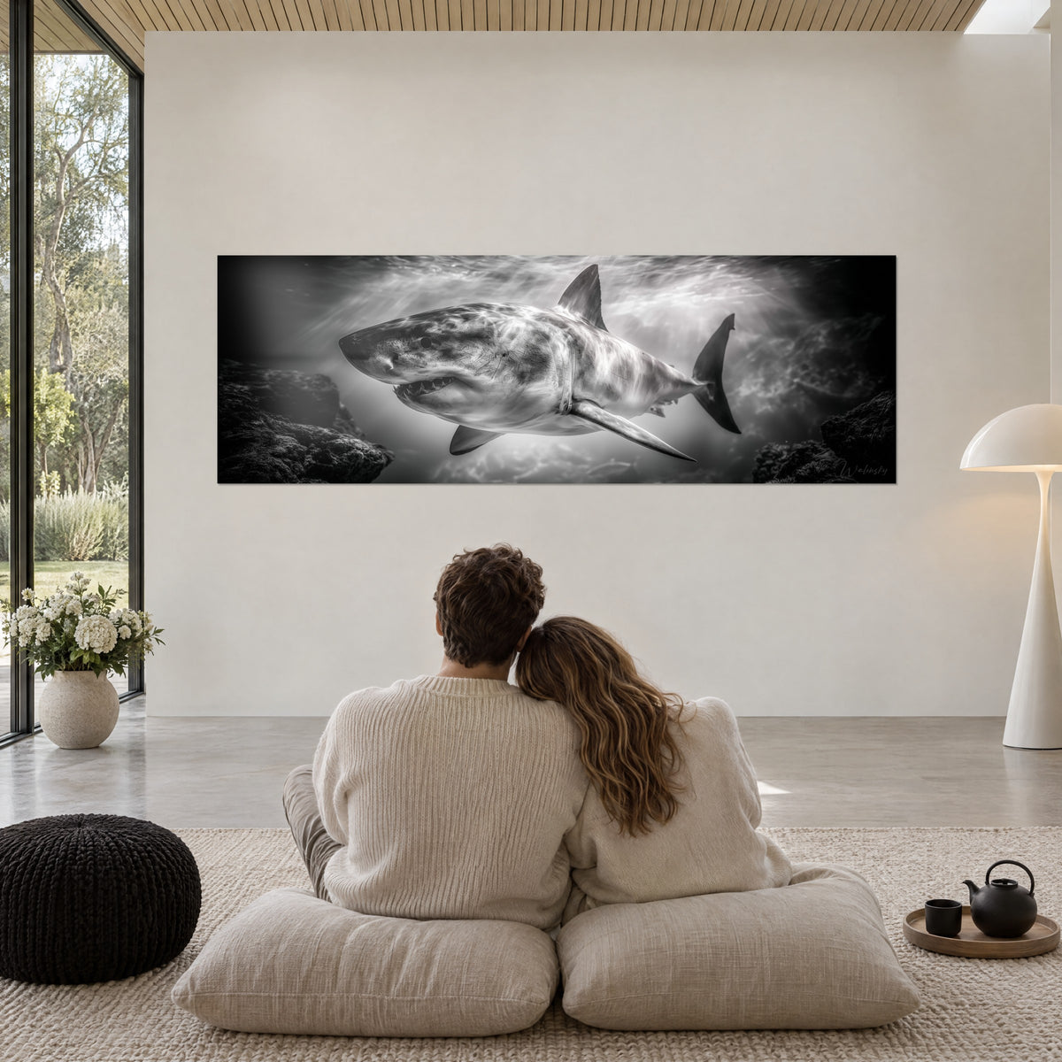 Schilderij van een monochrome haai tussen twee zwarte rotsmassa's, bleek licht van het wateroppervlak, groen getinte woonkamer, twee kussens op de vloer