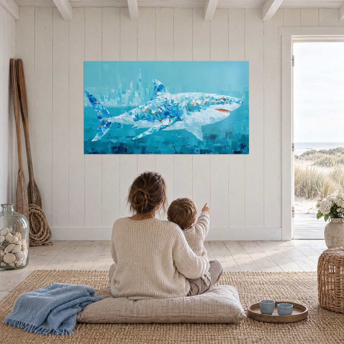 Tableau requin sur ville engloutie, aplats bleu pétrole et blanc nacré, vu par une mère et son enfant assis sur un futon