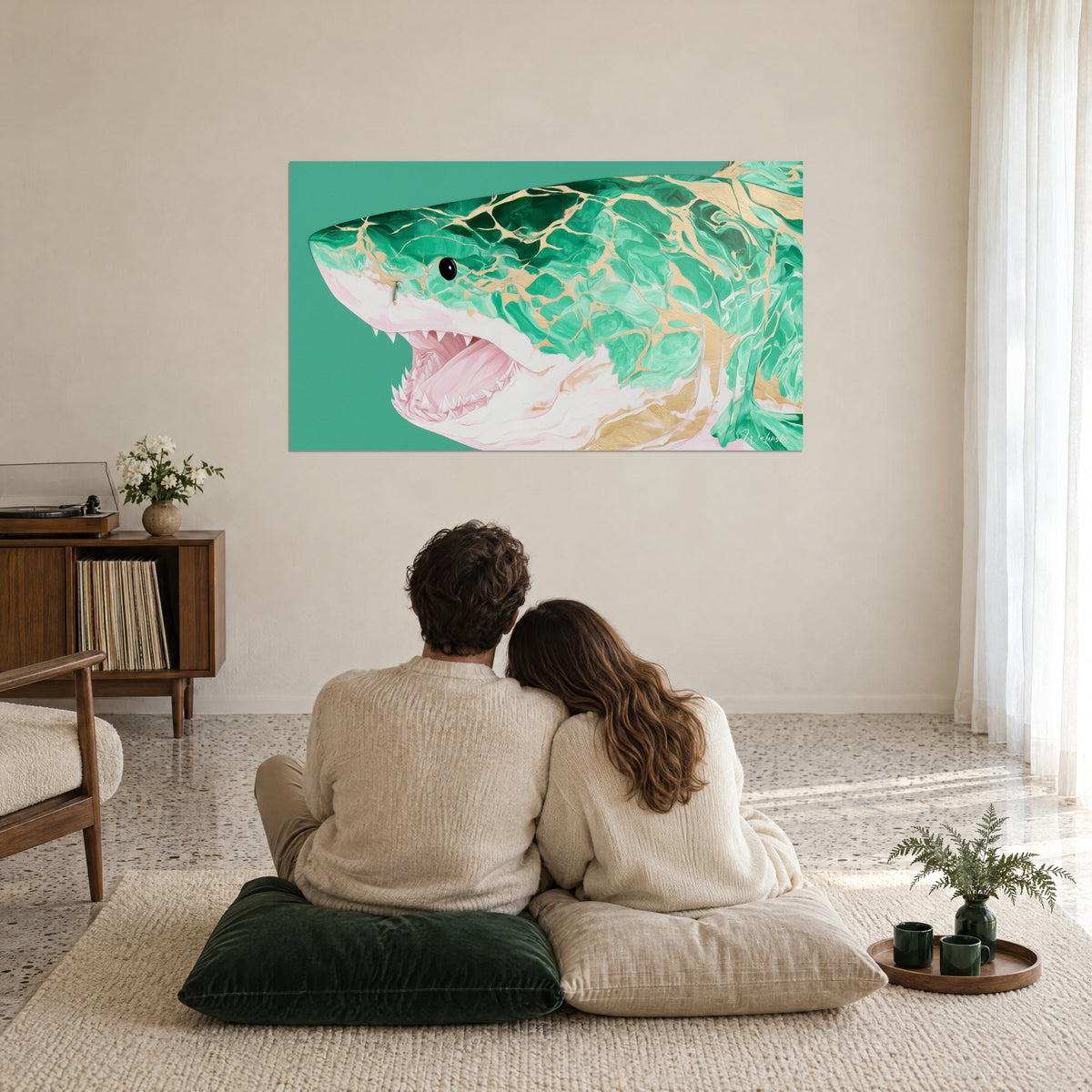 Tableau requin gueule ouverte aux reflets jade et or sur fond vert, regardé par un couple enlacé sur coussins, salon épuré