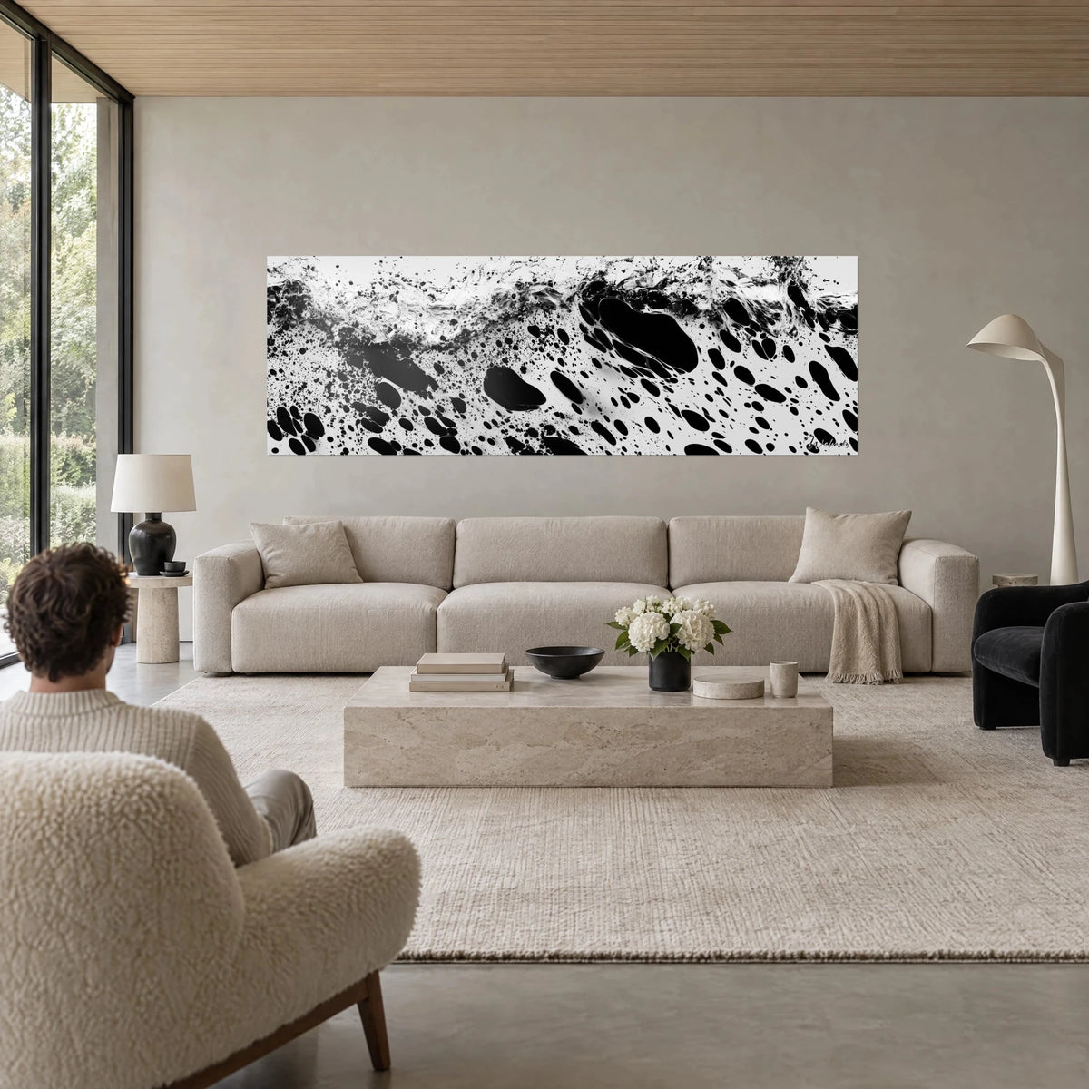 Tableau éclaboussure d'encre noire sur fond blanc, crête d'écume et gouttes ovales, au-dessus d'un canapé dans un salon lumineux