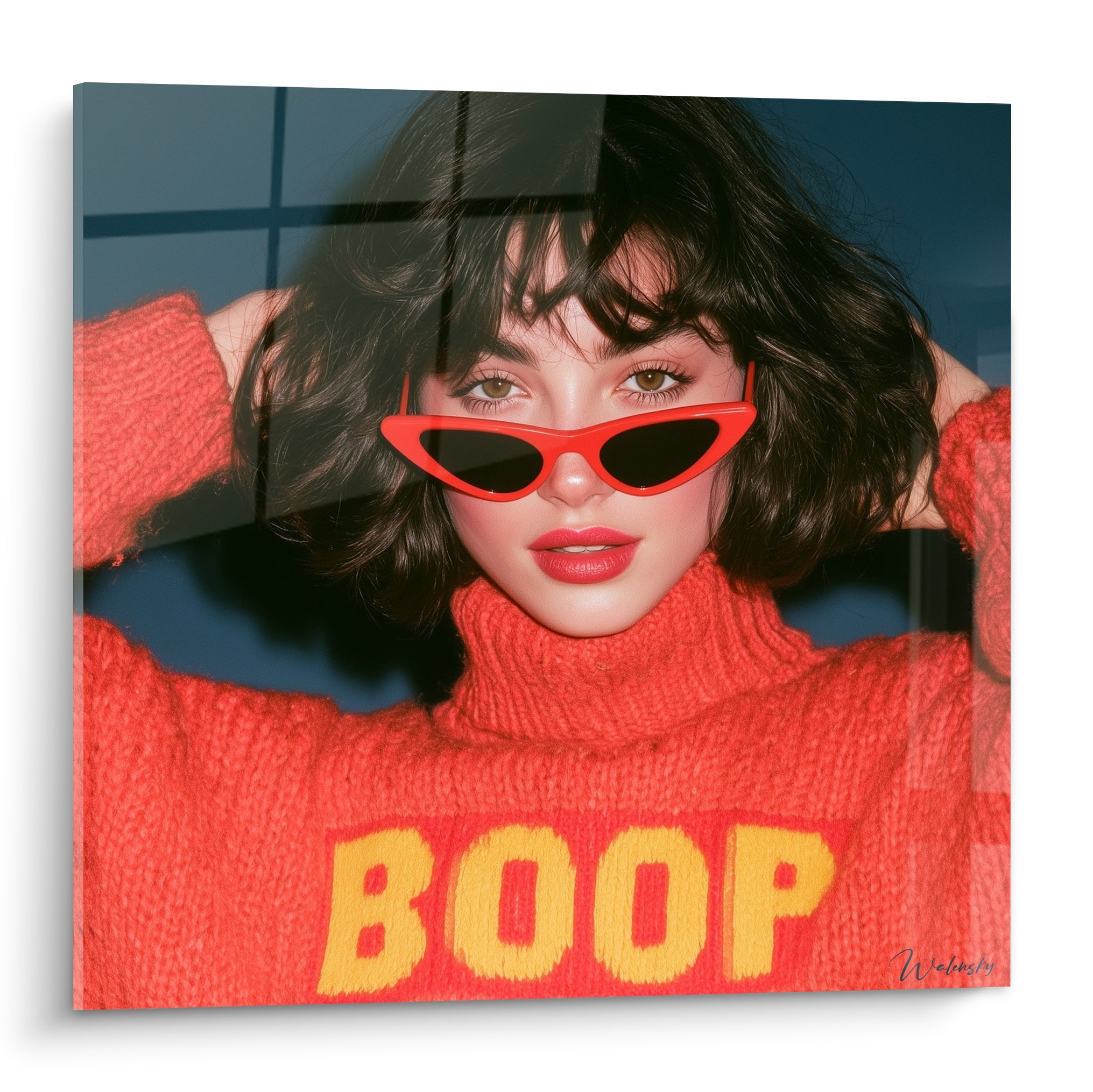 Femme aux lunettes rouges et pull orange BOOP, cheveux bruns bouclés, fond bleu quadrillé