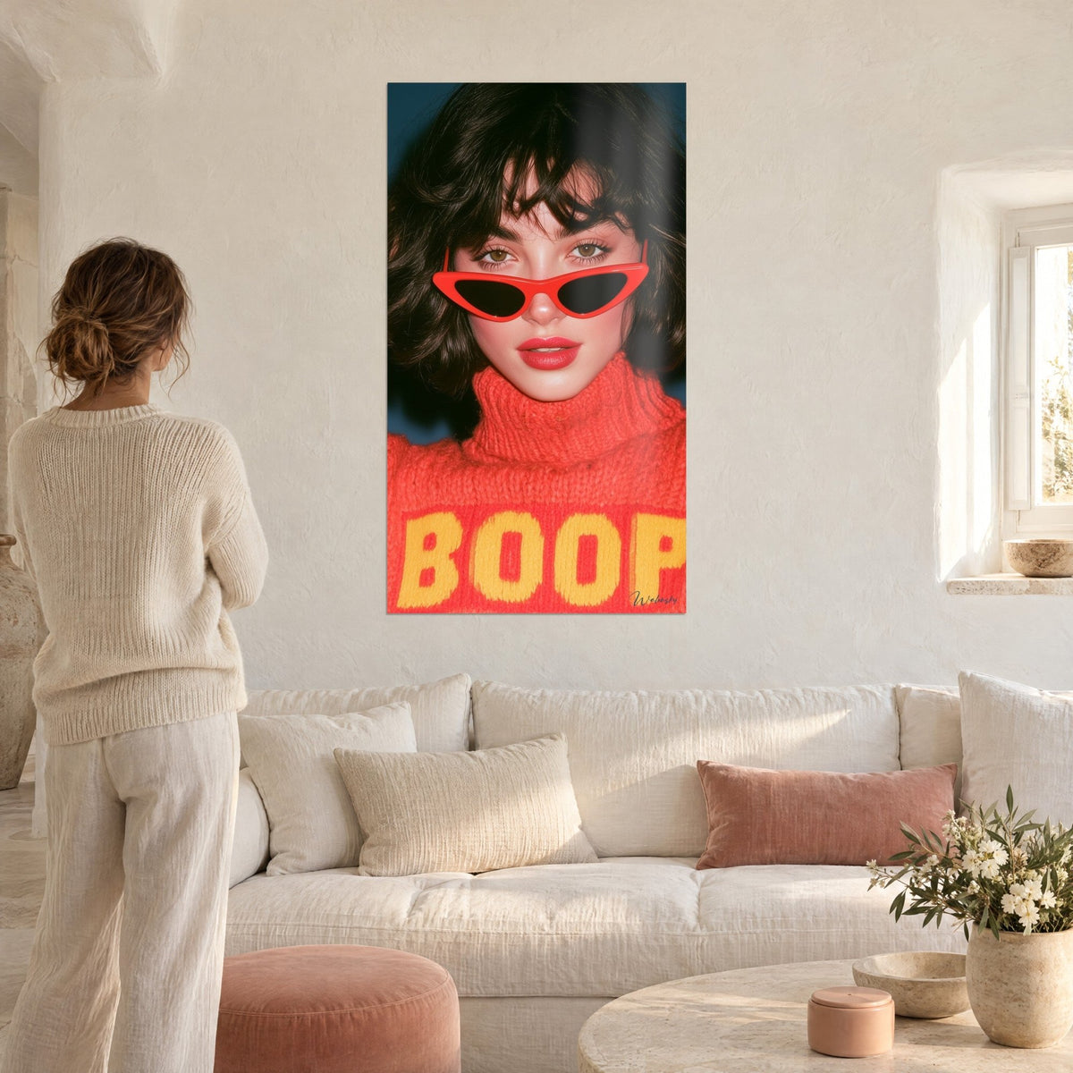 Cuadro retrato retro de una morena con gafas rojas y jersey naranja, letras amarillas, encima de un sofá en un salón luminoso