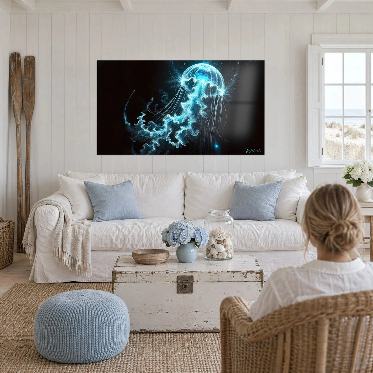 Gemälde einer leuchtenden Qualle mit cyanfarbenen Fäden auf schwarzem Grund, eine Frau von hinten, über einem Sofa in einem hellen Wohnzimmer