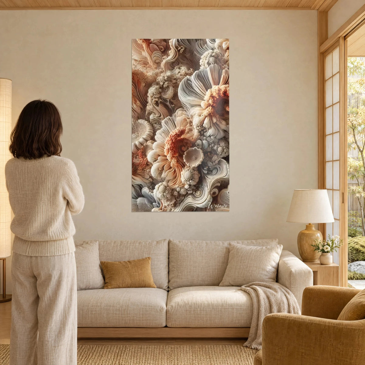 Tableau fleurs sculptées en volutes ivoire et corail, une femme de dos le contemple au-dessus d'un canapé dans un salon lumineux