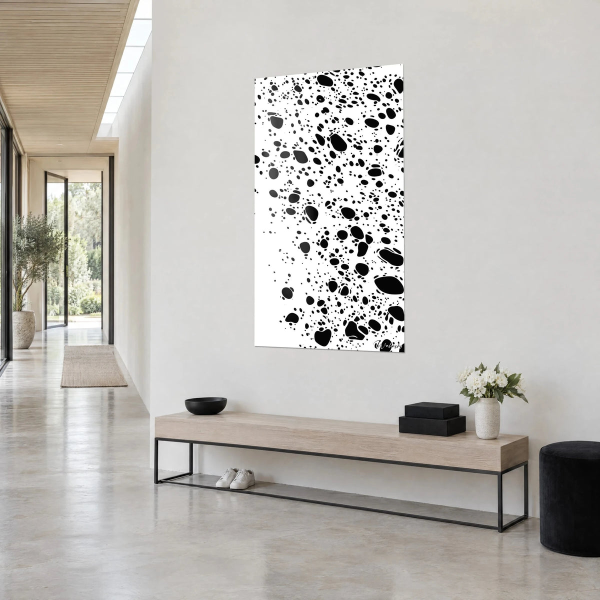 Wall art with black drops scattered like a swarm on white, vertical, seen at an angle, light wood console, in a bright hallway