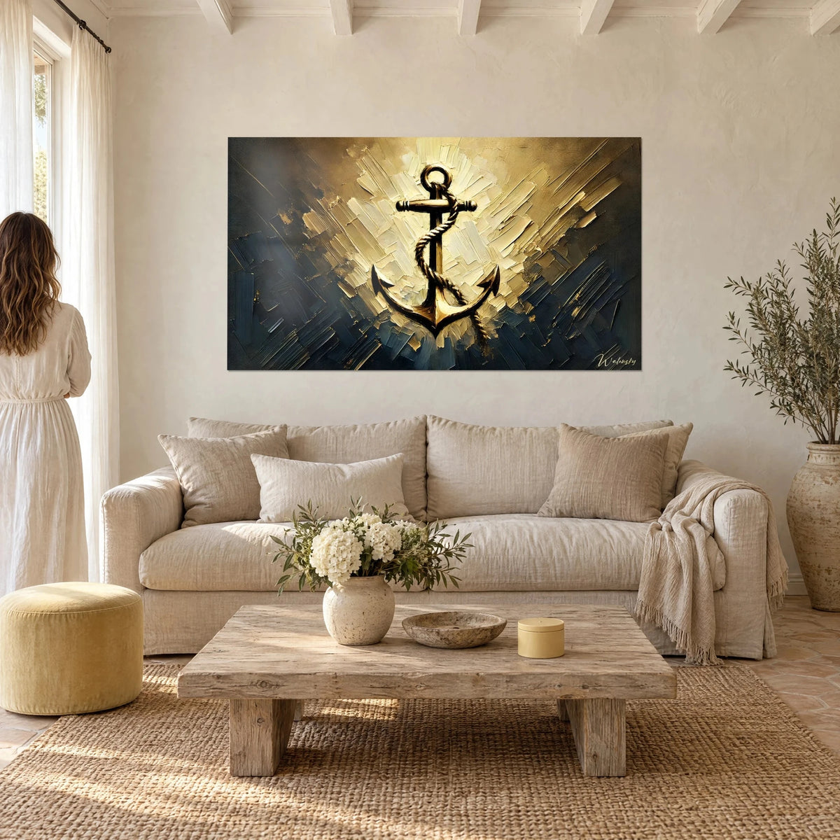 Quadro con un'ancora dorata avvolta da una corda, sfondo avorio e blu notte, coppia di spalle, sopra un divano in un soggiorno luminoso