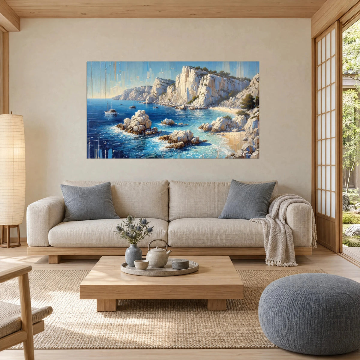 Tableau calanque aux falaises blanches et mer indigo, voiliers au loin, au-dessus d'un canapé dans un salon lumineux