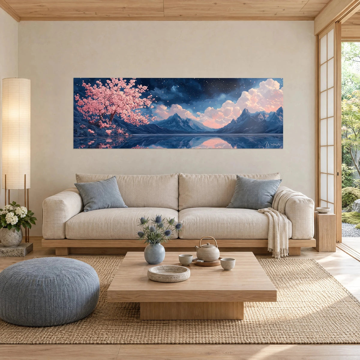 Wall art of a powder-pink cherry tree in bloom facing steel-blue peaks and peach clouds, hung above a sofa in a bright living room