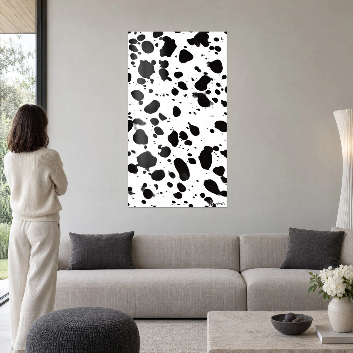 Cuadro con motivo dálmata en blanco y negro, grandes manchas de tinta sobre fondo marfil, encima de un sofá en un salón luminoso