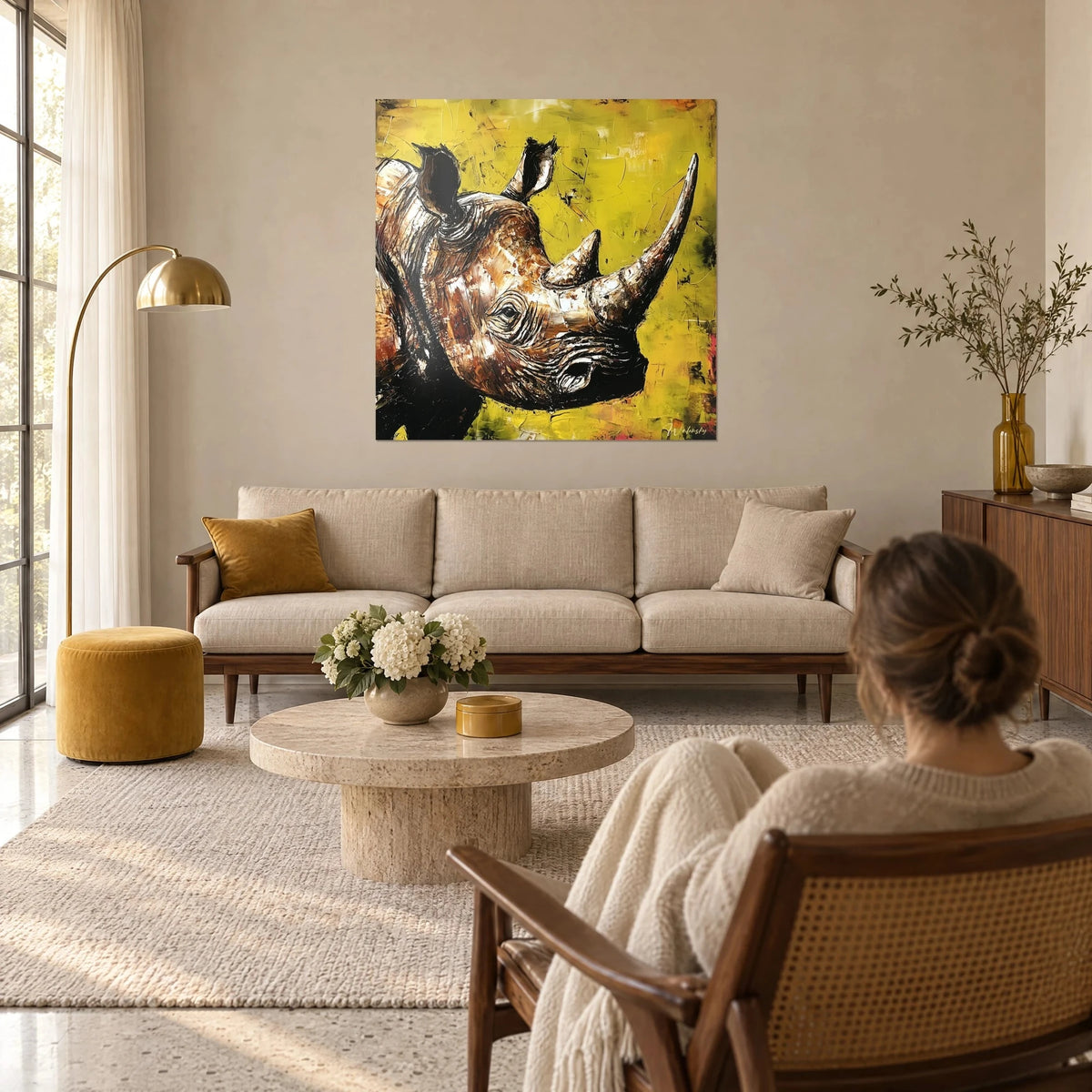 Tableau rhinocéros à la corne dressée, peinture au couteau brun roux sur fond jaune anis, au-dessus d'un canapé dans un salon lumineux