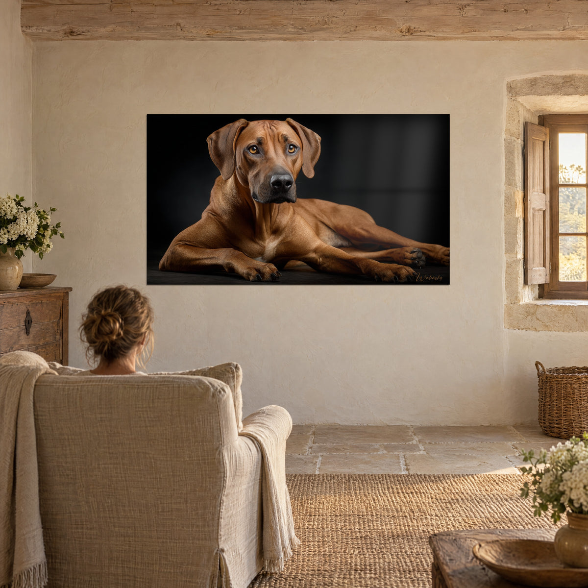 Πίνακας: γλυπτικό Ridgeback με τρίχωμα καστανιάς, βλέμμα προς εμάς, άτομο από πίσω σε λινή πολυθρόνα, πέτρινο σαλόνι