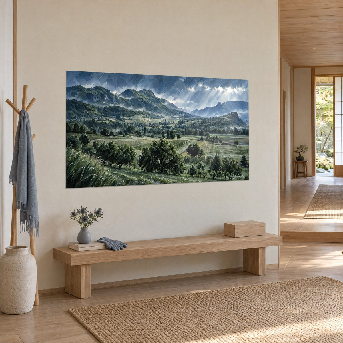 Wall art of a mountain landscape under a stormy sky, white church steeple in the distance and olive green fields, on a beige wall beside a wooden bench