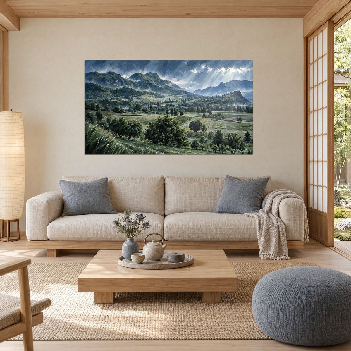 Wall art of a green valley with bluish ridges, stormy grey clouds and soft green meadows, above a sofa in a bright living room