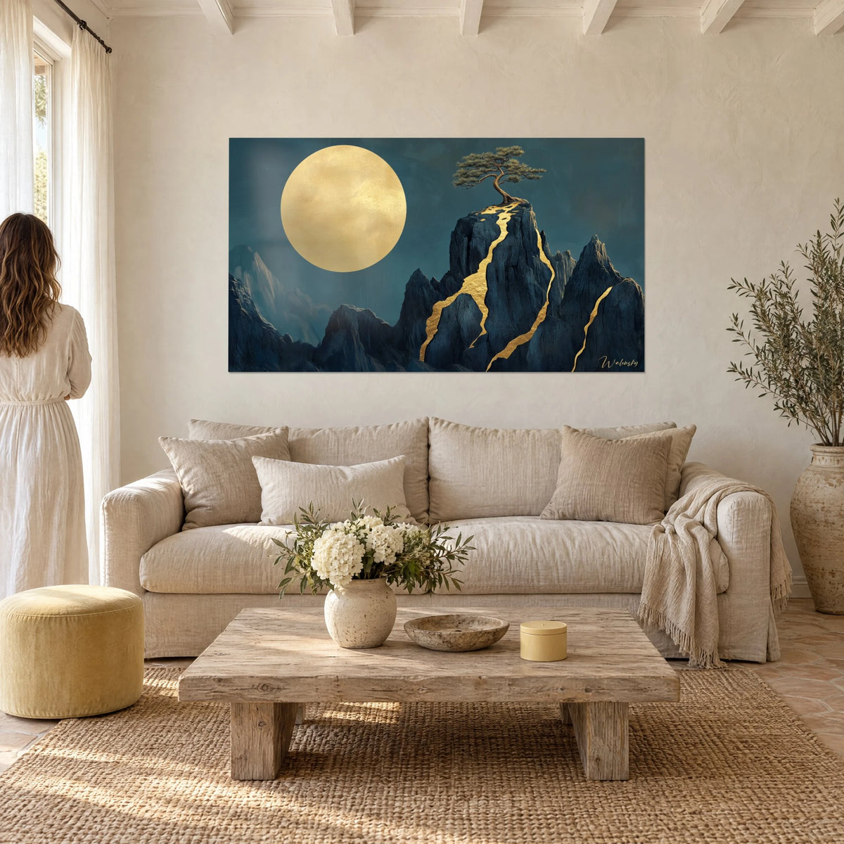 Wall art golden full moon above a midnight-blue peak veined with gold, twisted pine at the summit, above a sofa in a bright living room