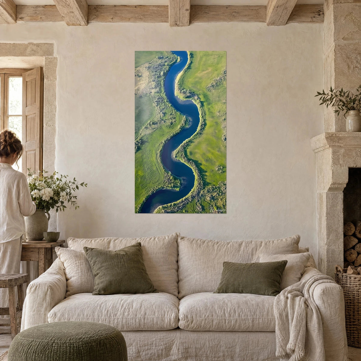 Wall art of a winding deep blue river snaking through soft green meadows, aerial view, hung above a sofa in a bright living room
