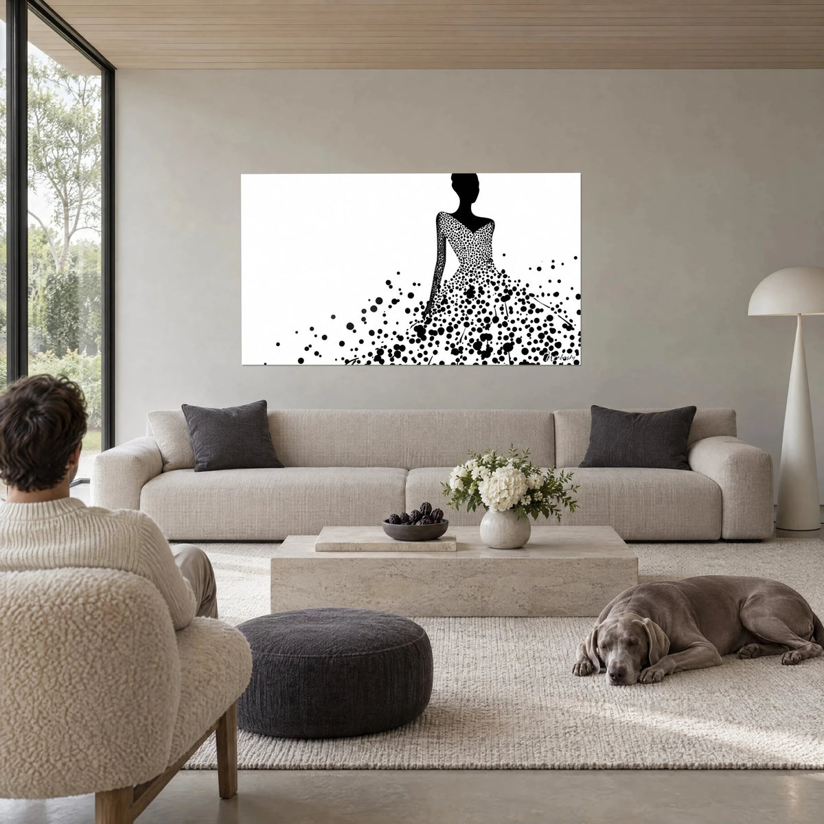 Tableau silhouette noire en robe de bal pointillée, taches d'encre sur fond blanc, au-dessus d'un canapé dans un salon lumineux
