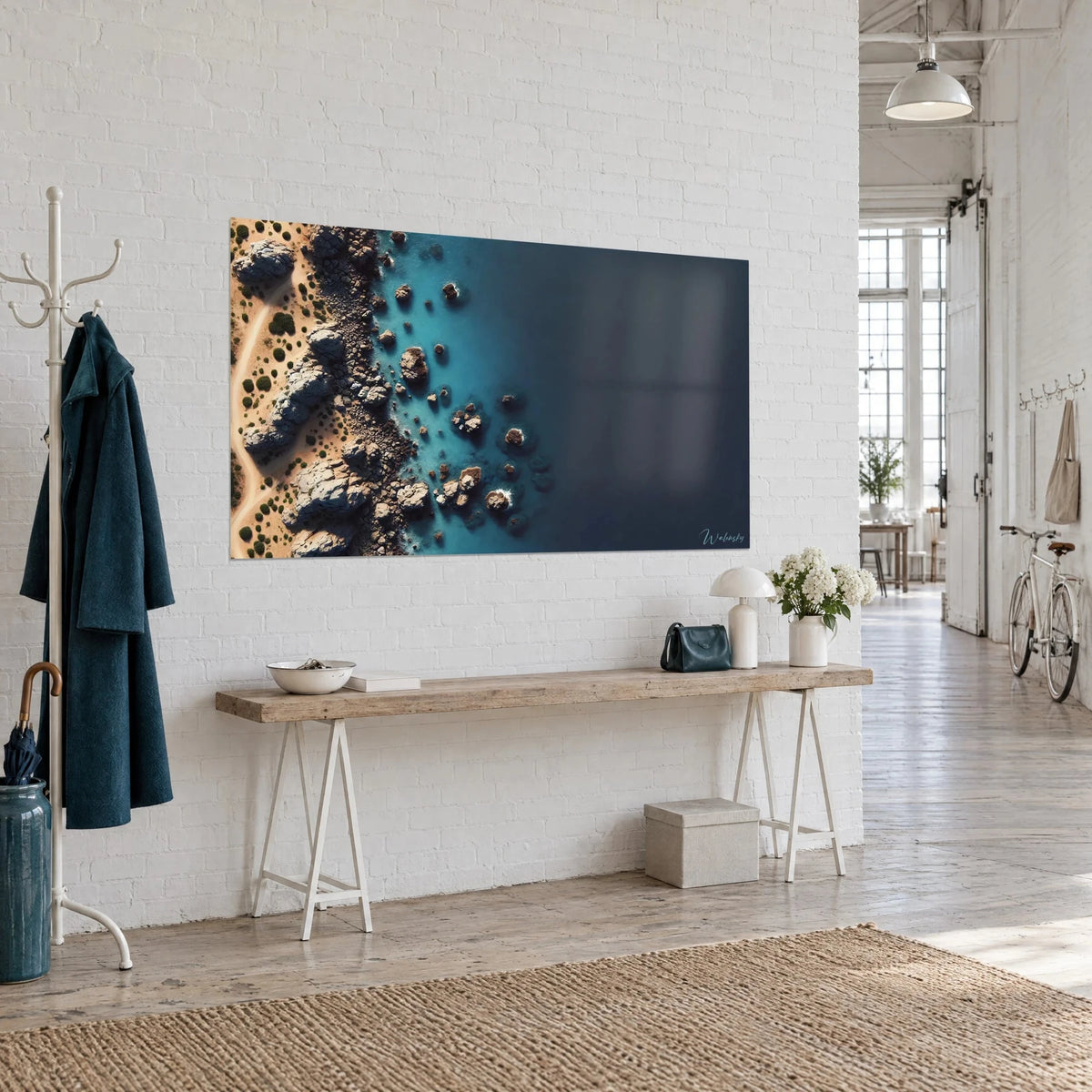 Schilderij wilde kustlijn van bovenaf, bruine riffen bespikkeld met schuim, turquoise zee die in inkt overgaat, aan een witte loftmuur