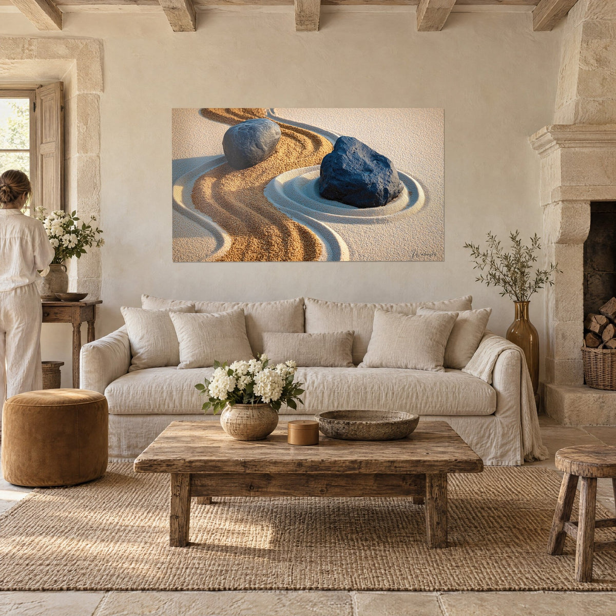 Tableau jardin zen en sable, galet noir et ruban doré ondulant, une personne de dos au-dessus d'un canapé dans un salon lumineux