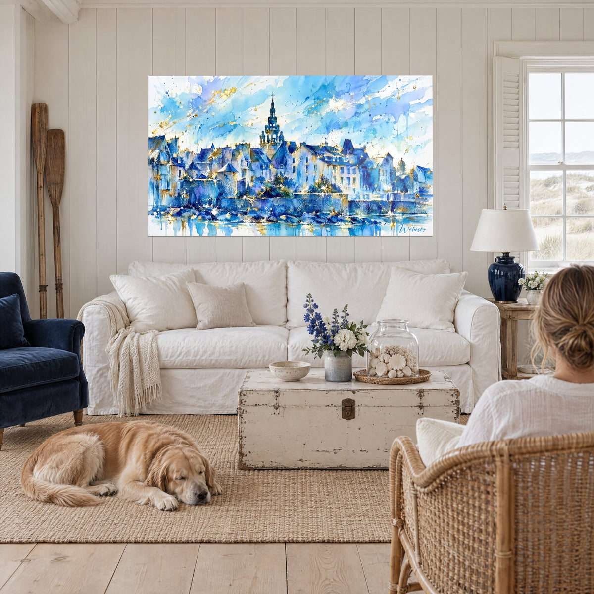 Gemälde mit Kirchturm und Granithäusern in Aquarell, kobaltblau und Gold, liegender Retriever, über einem Sofa in einem hellen Wohnzimmer