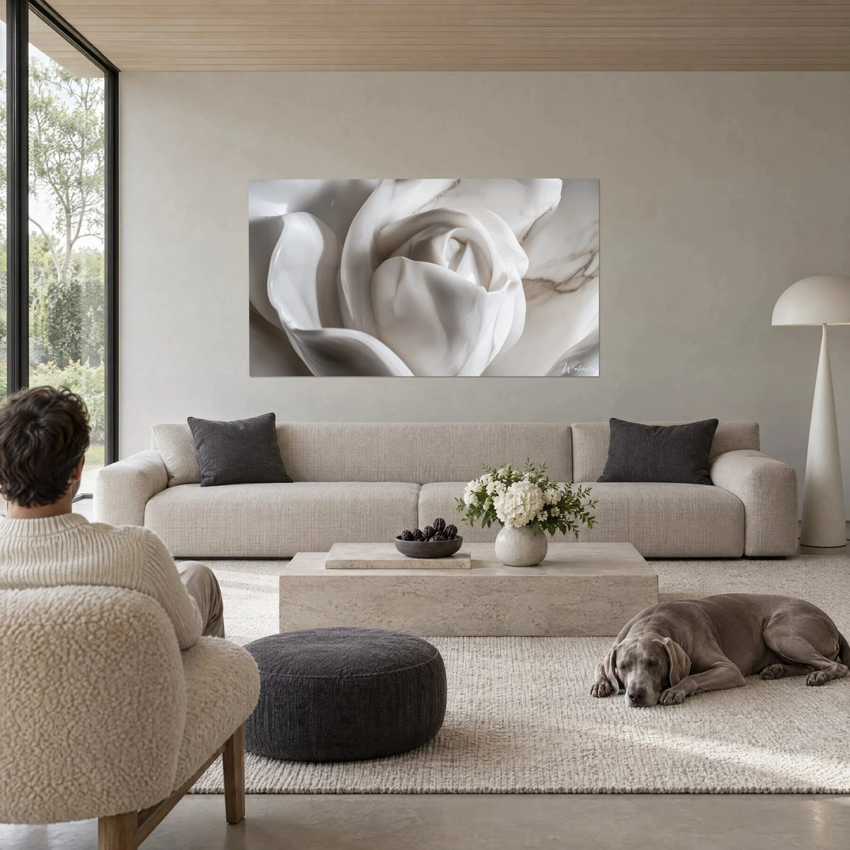 Tableau rose sculptée en marbre blanc aux veines grises, pétales en volutes, au-dessus d'un canapé dans un salon lumineux