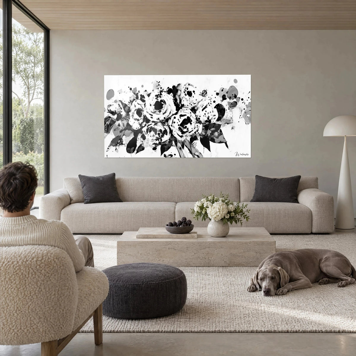 Tableau bouquet de roses éclaboussées en noir et blanc, taches d'encre sur fond blanc, au-dessus d'un canapé dans un salon lumineux
