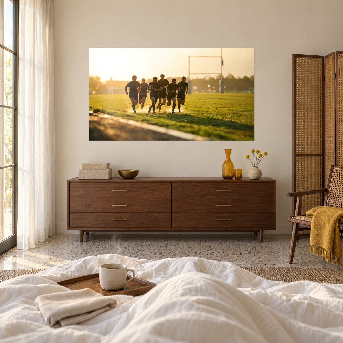 Wall art group of dark forwards charging toward the posts, vivid green grass and orange evening light, above a bed in a light bedroom