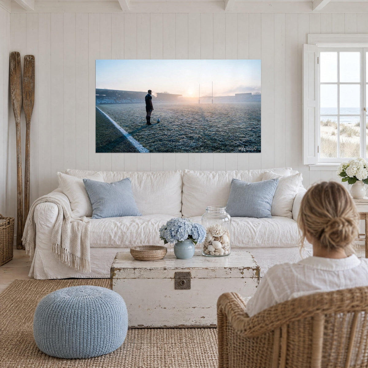 Tableau joueur de rugby en maillot bleu marine sur gazon givré, soleil rose pâle, au-dessus d'un canapé dans un salon lumineux