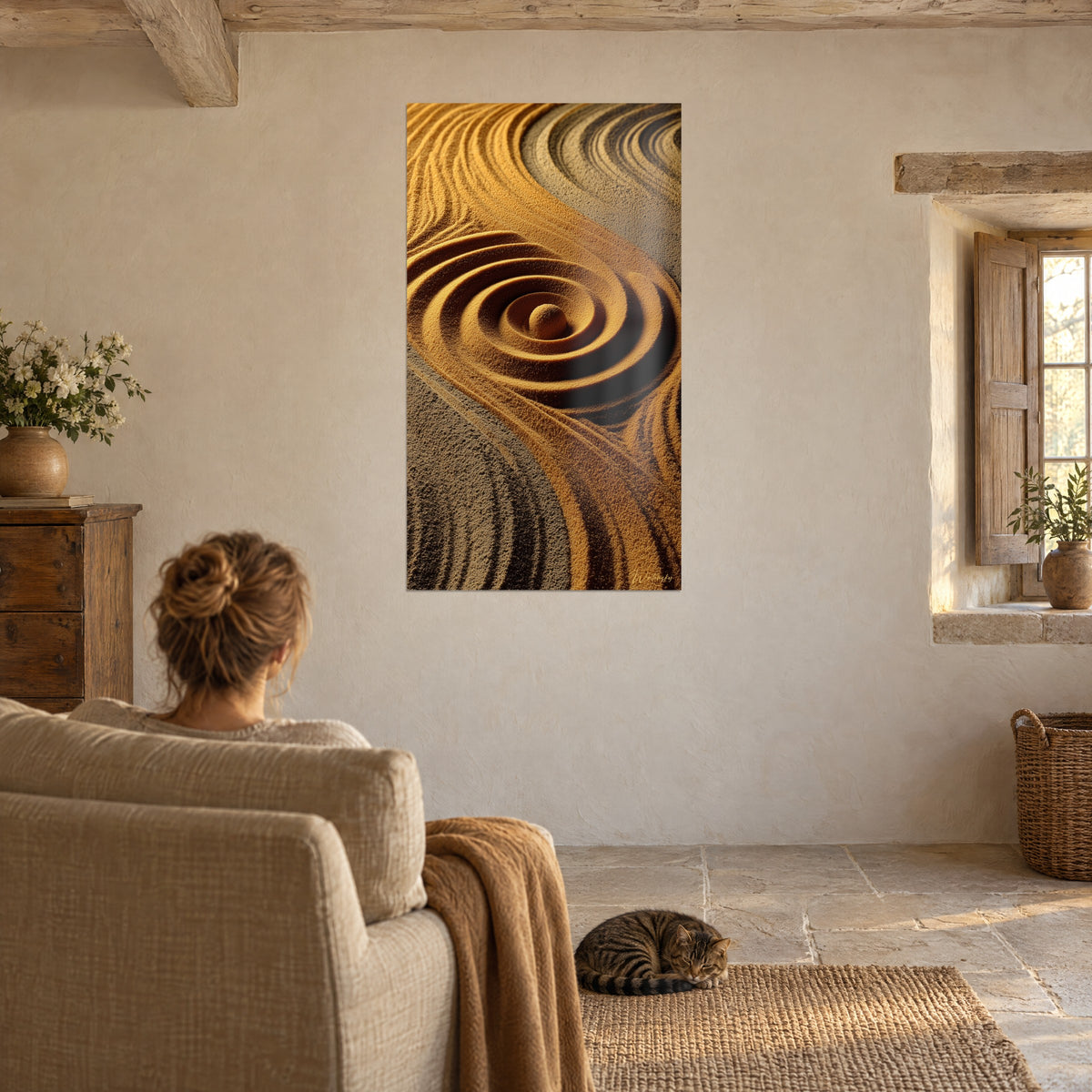 Quadro volute di granelli dorati e marroni attorno a un ciottolo di sabbia, con un gatto tigrato sul tappeto di juta