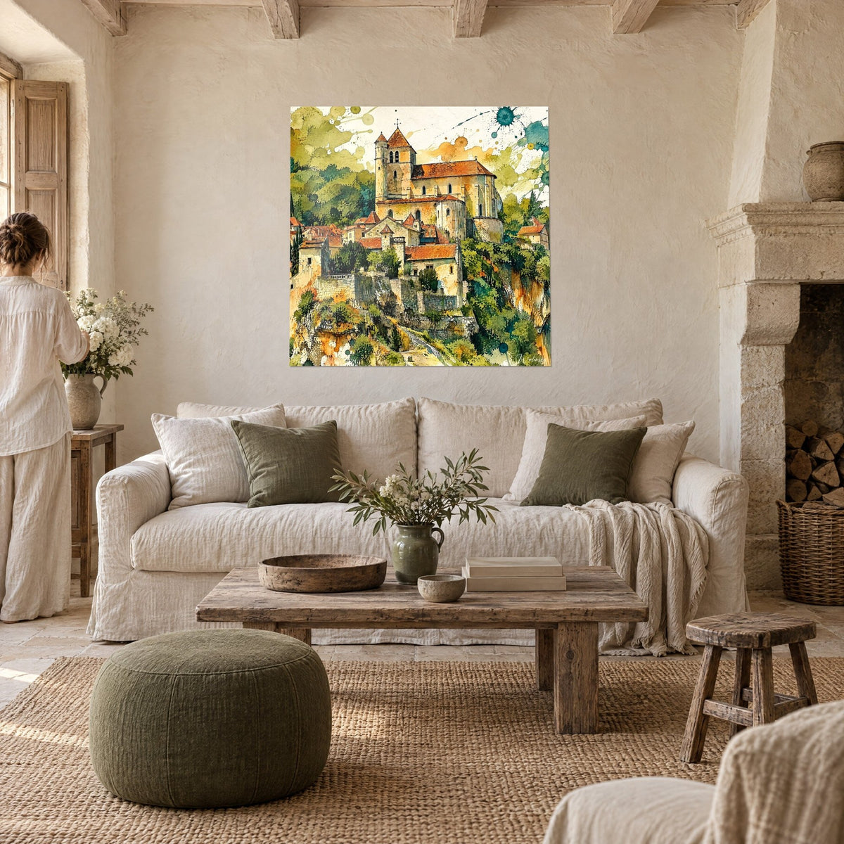 Quadro di un villaggio medievale arroccato, chiesa con tetti di tegole arancioni e verde, persona di spalle, sopra un divano in un soggiorno luminoso