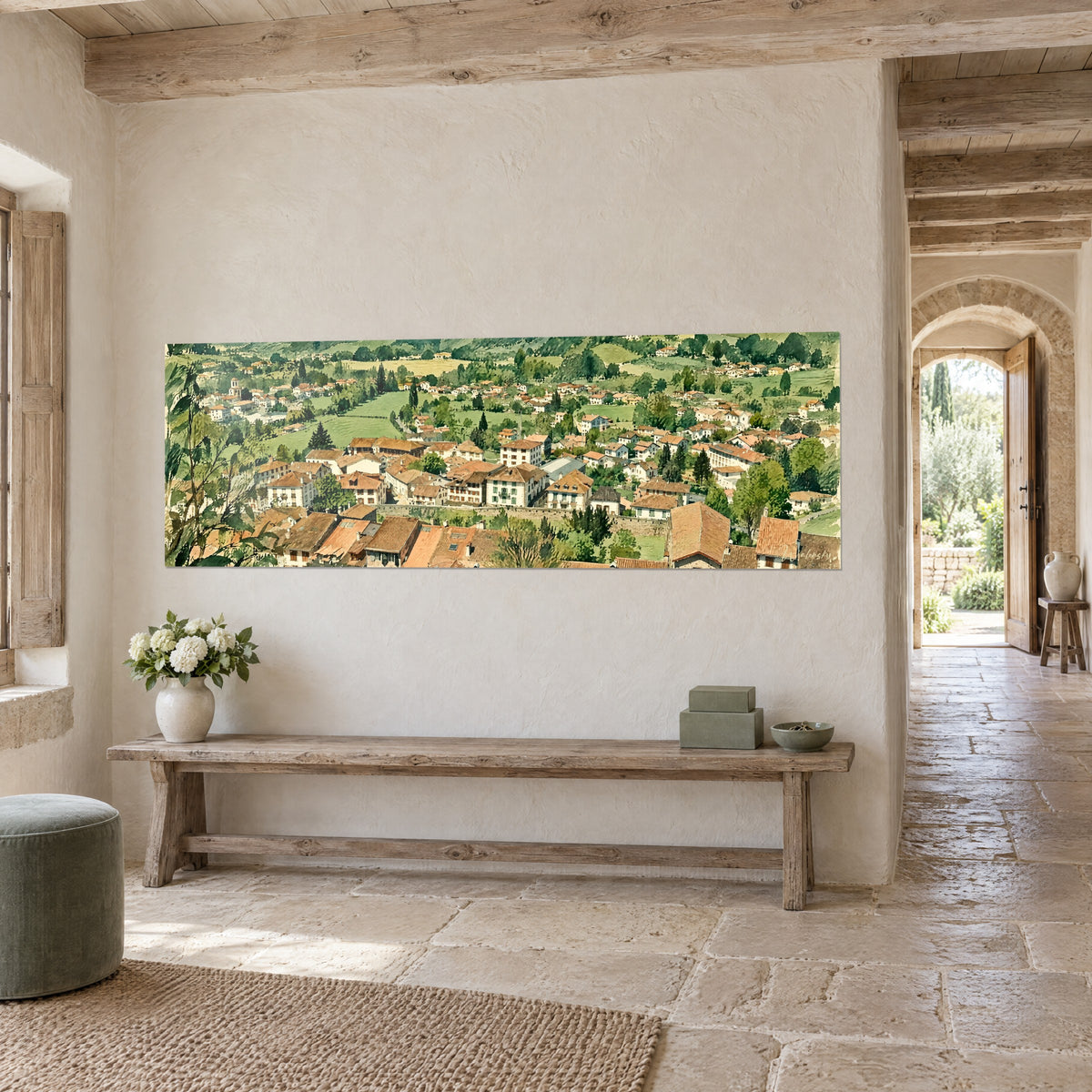 Collines vertes entourant un village aux toits rouges et maisons crème, au-dessus d'un canapé dans un salon lumineux