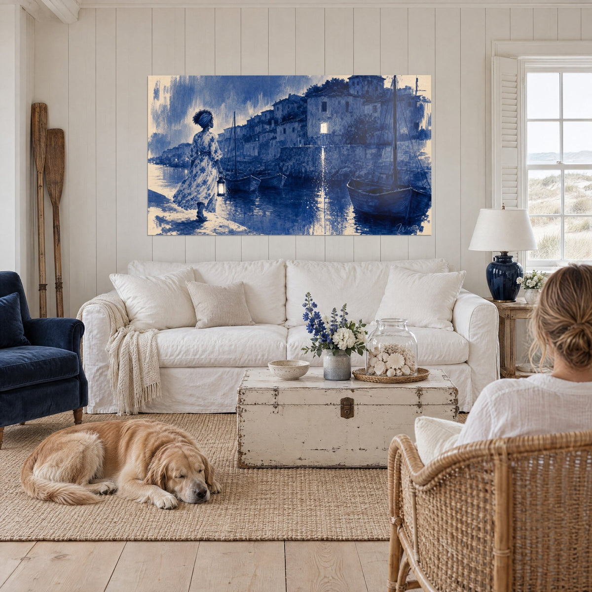 Quadro di una donna con lanterna che costeggia un molo blu cobalto e crema, barche ormeggiate, sopra un divano in un soggiorno luminoso