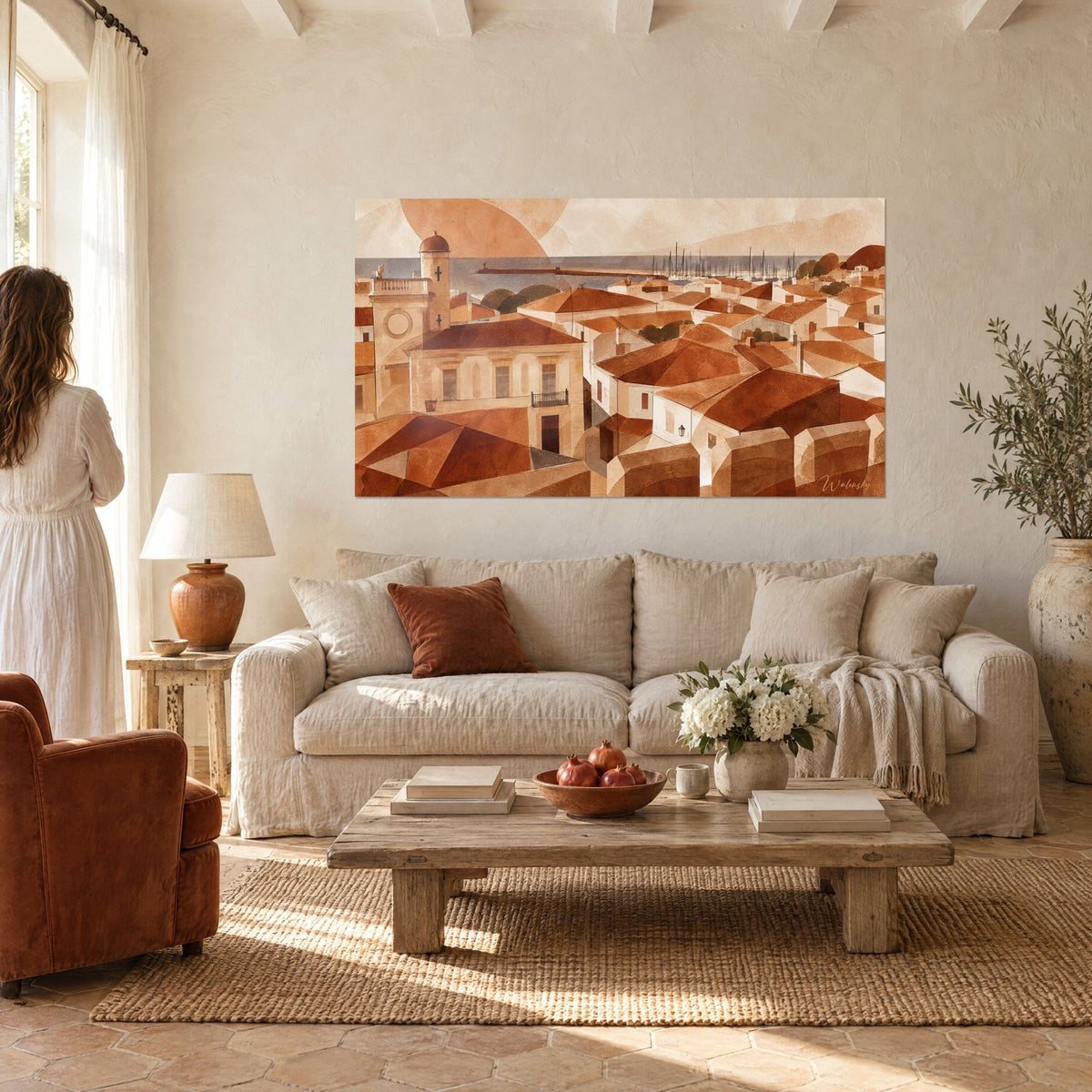 Quadro di una chiesa fortificata con tetti terracotta e beige, croce scura sul campanile, mare grigio sullo sfondo, sopra un divano in un soggiorno luminoso