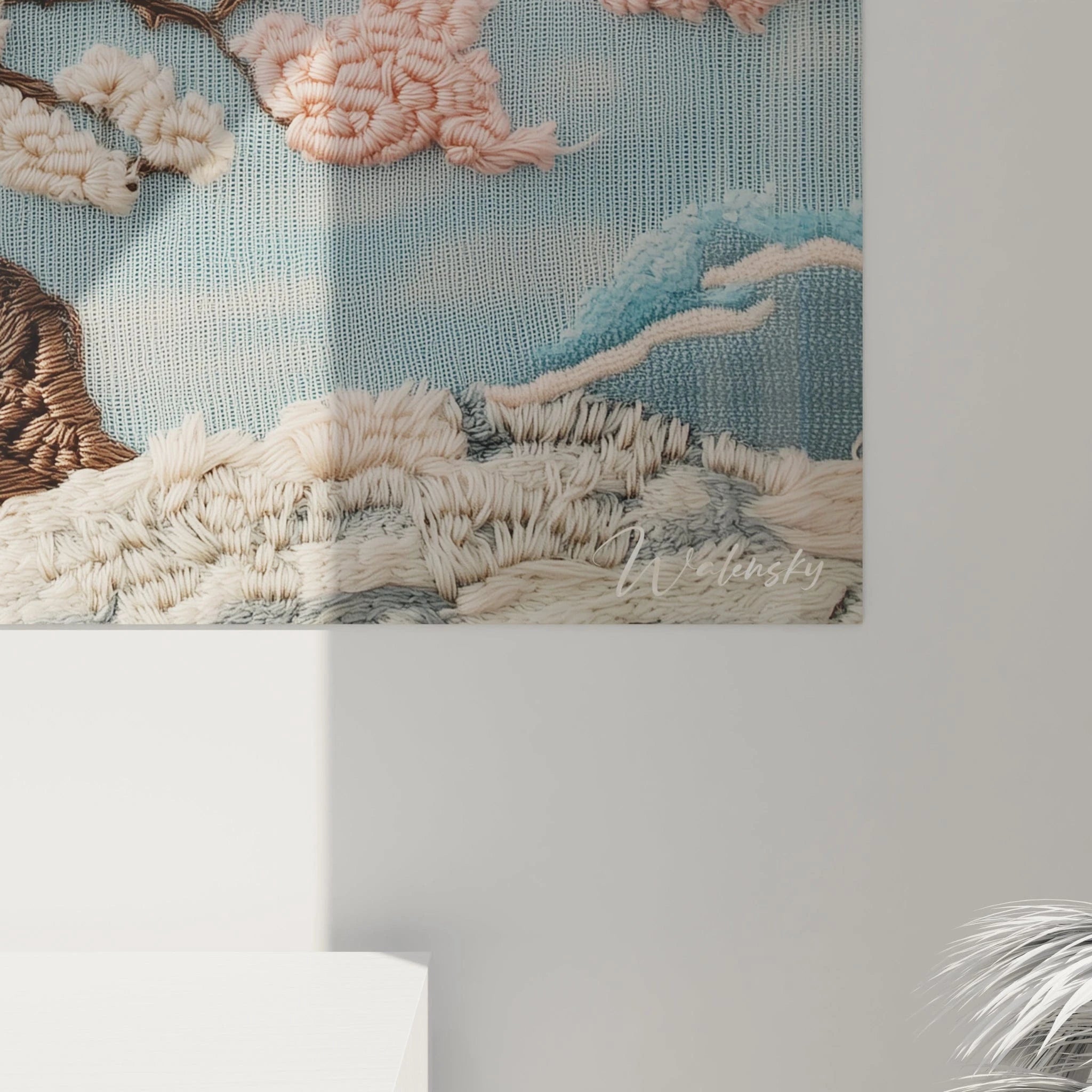 Un tableau textile au point de crochet mettant en scène un cerisier japonais dont les fleurs roses et blanches ressortent en relief sur un fond bleu ciel apaisant, avec des nuages blancs cotonneux et des vagues bleues stylisées.