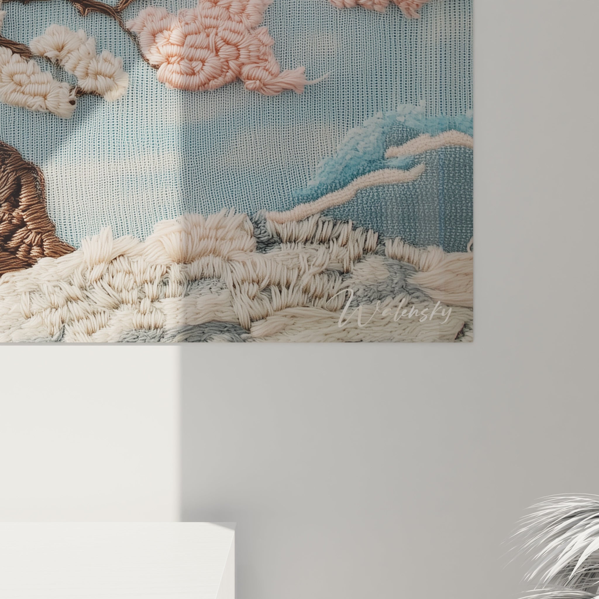 Un tableau textile au point de crochet mettant en scène un cerisier japonais dont les fleurs roses et blanches ressortent en relief sur un fond bleu ciel apaisant, avec des nuages blancs cotonneux et des vagues bleues stylisées.