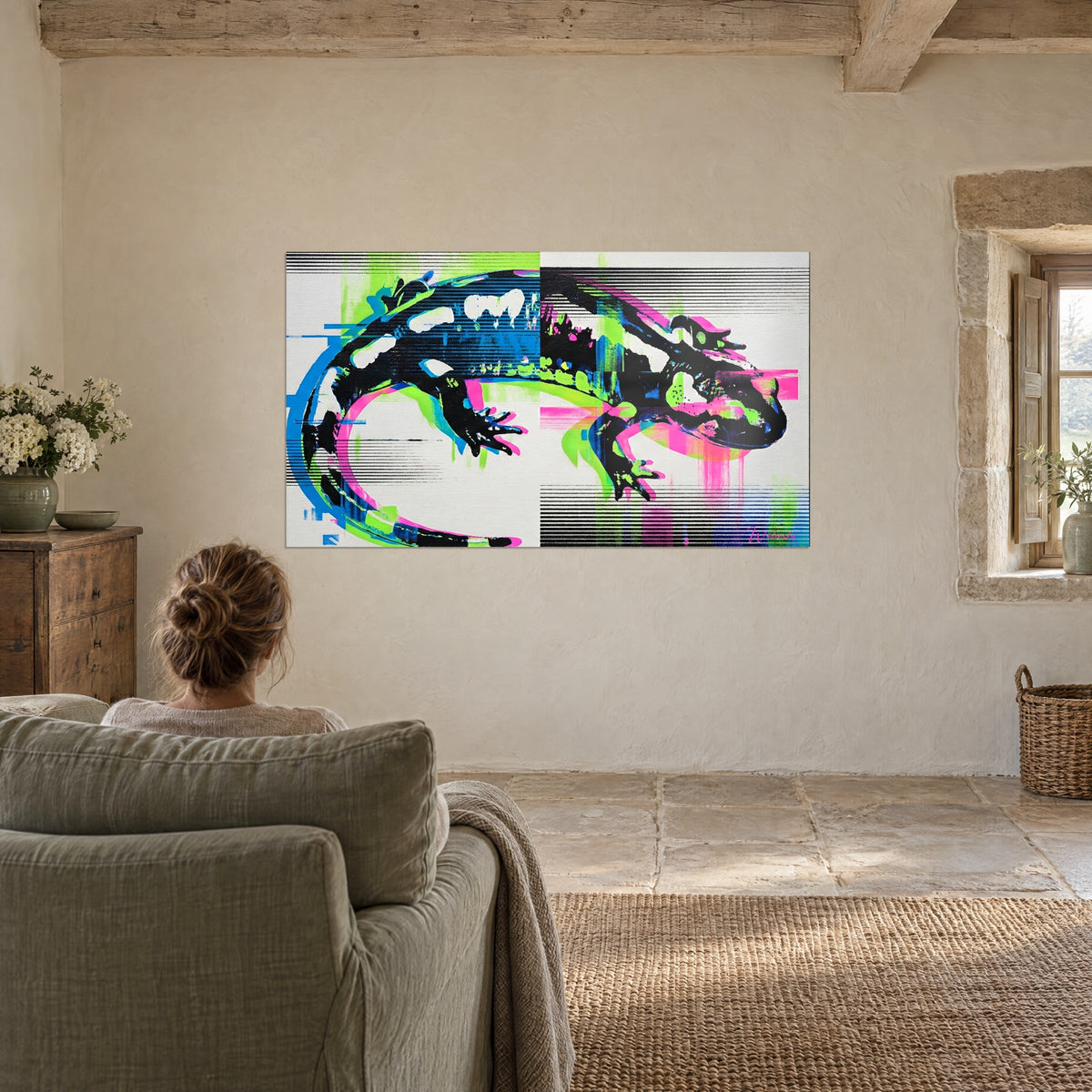 Wall art black pop art salamander crossed by acid green and pink bands, a woman seen from behind seated in a sage armchair facing the wall