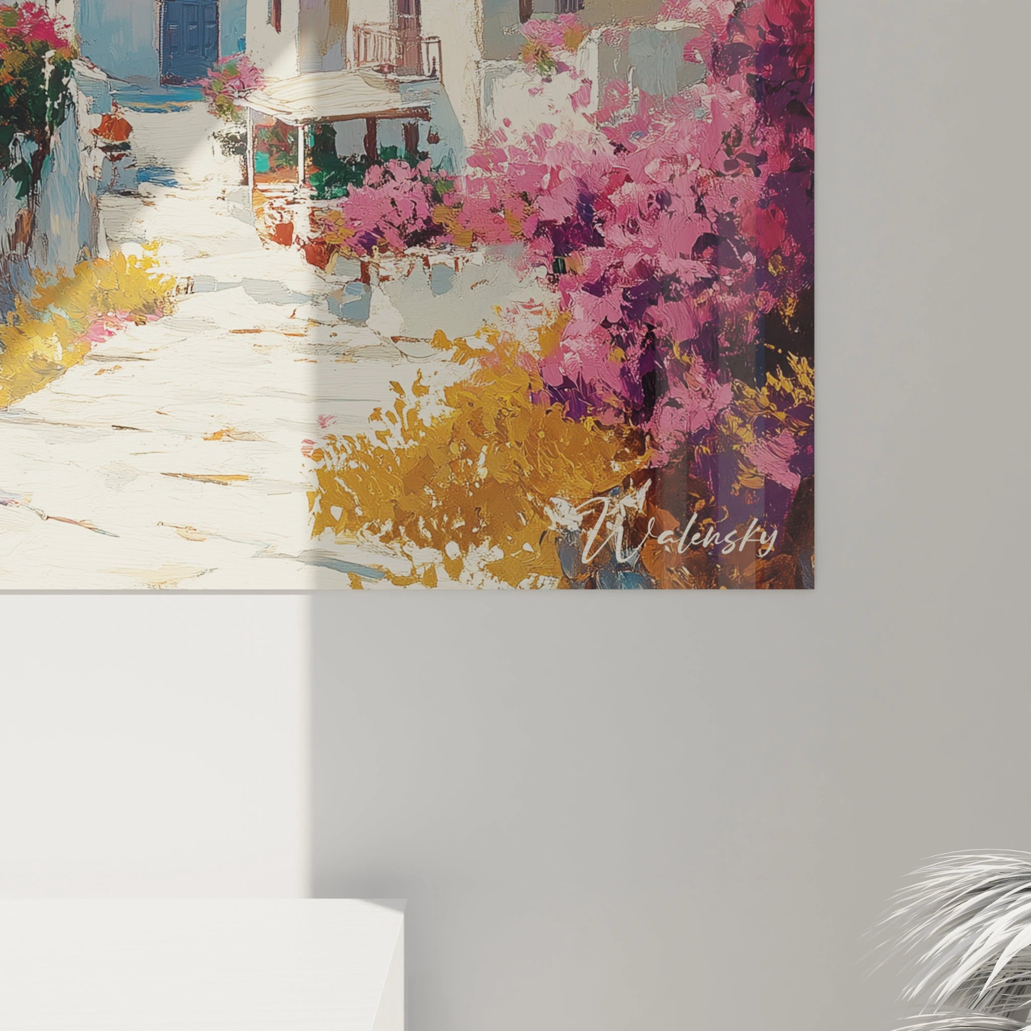 Un tableau côtier grec présentant un ensemble architectural blanc immaculé sur promontoire rocheux, encadré par des masses florales roses vibrantes, contrastant avec le bleu intense de la mer et le ciel lumineux.
