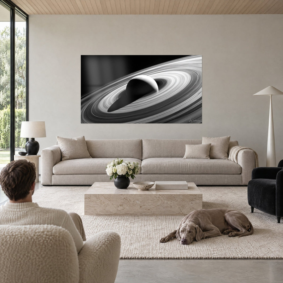 Tableau Saturne et ses anneaux en noir et blanc, boule grise ombrée, stries argentées, au-dessus d'un canapé dans un salon lumineux