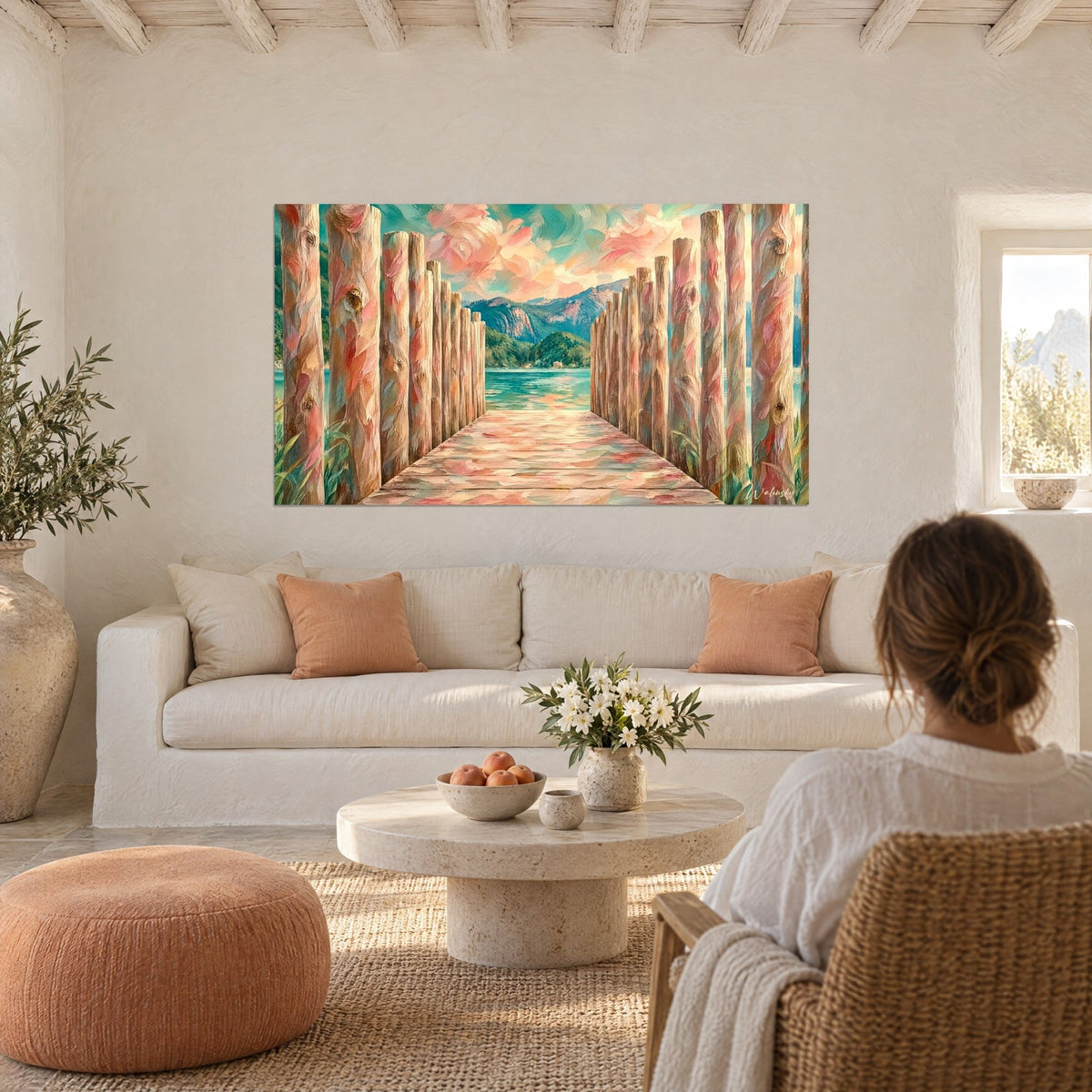 Schilderij houten steiger in roze en turquoise, omzoomd door knoestige palen, groen meer en bergen, van achteren gezien boven een bank in een lichte woonkamer